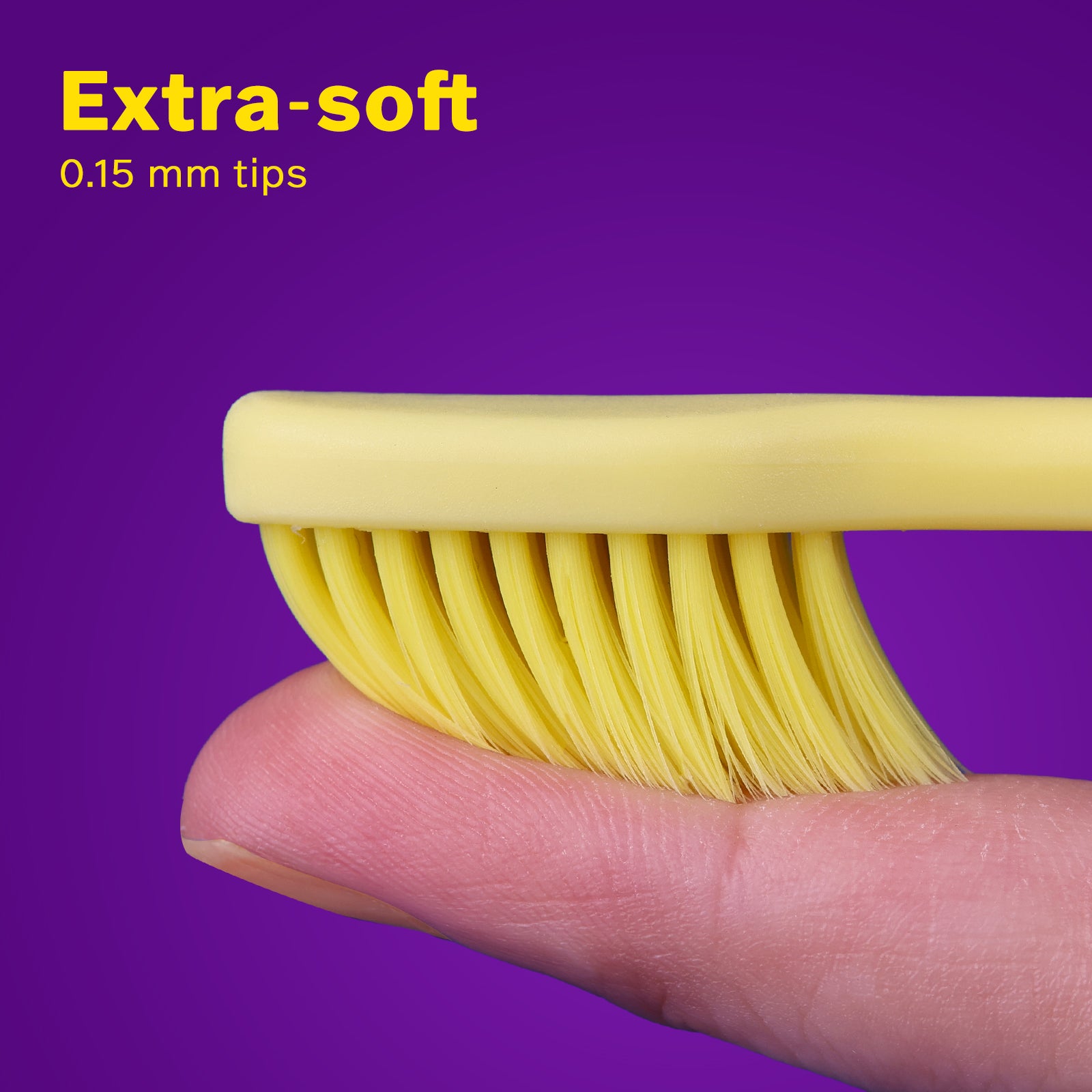 Close-up of extra-soft 0.15 mm yellow dental brush bristles gently pressed on a finger