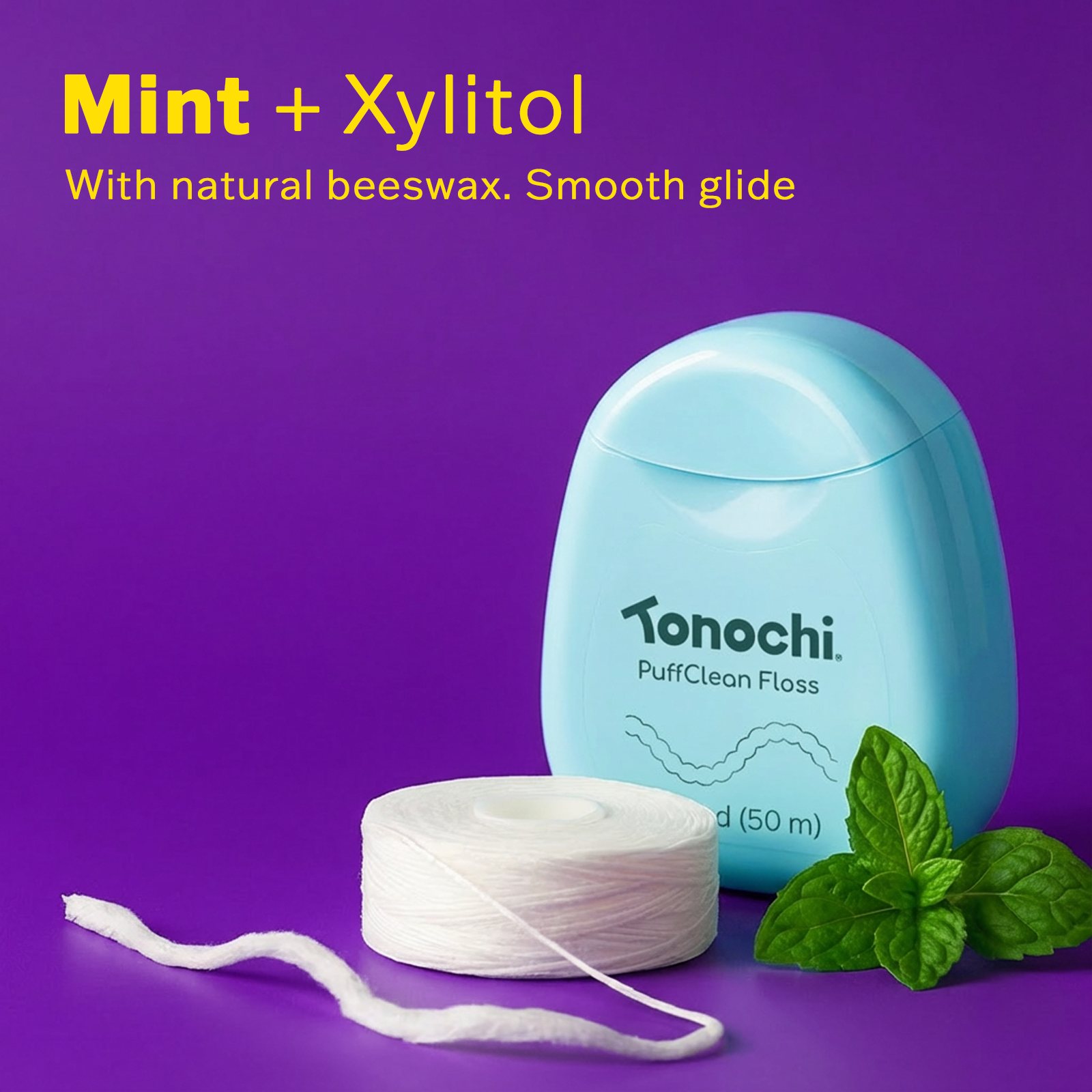 Mint + Xylitol Tonochi PuffClean Floss in a blue container, with natural beeswax and mint leaves on a purple background.