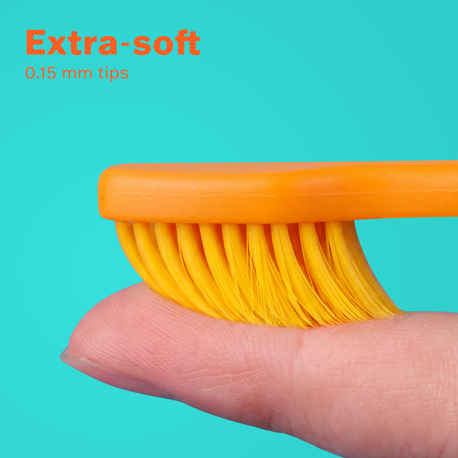 Close-up of extra-soft 0.15 mm orange dental brush bristles gently pressed on a finger