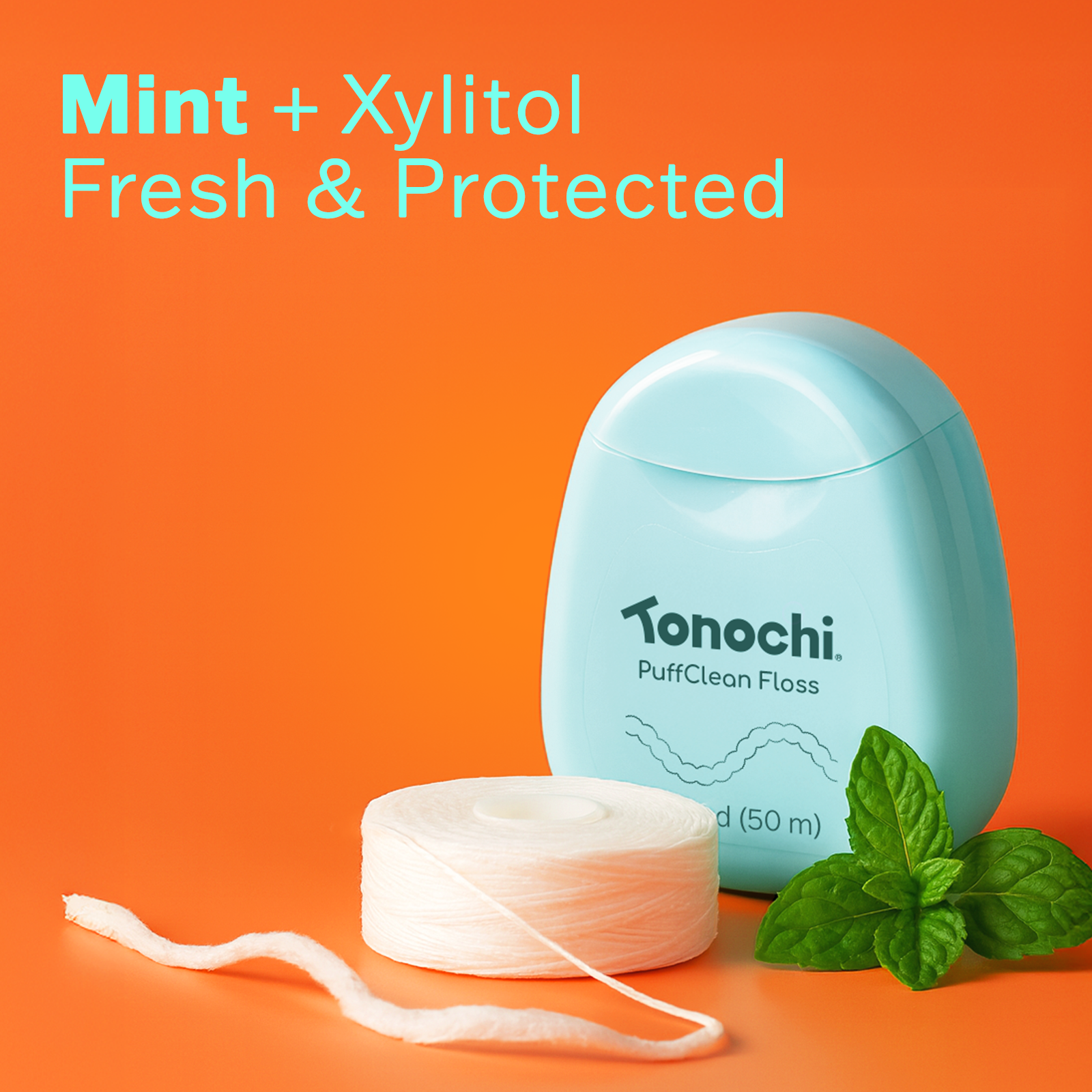 Tonochi PuffClean dental floss dispenser with fresh mint leaves, highlighting the mint and xylitol infusion.