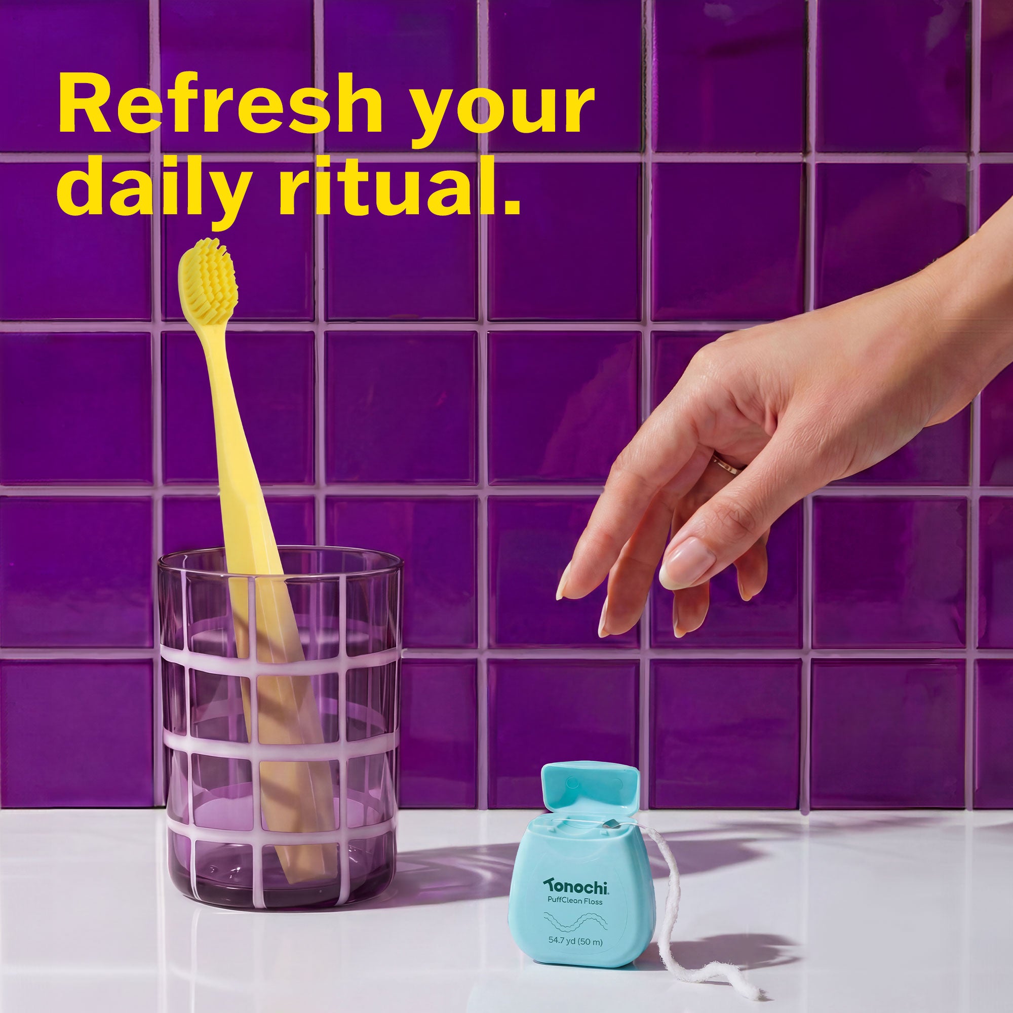 Refresh your daily ritual with a yellow toothbrush in a glass and a teal Tonochi floss against a purple backdrop.