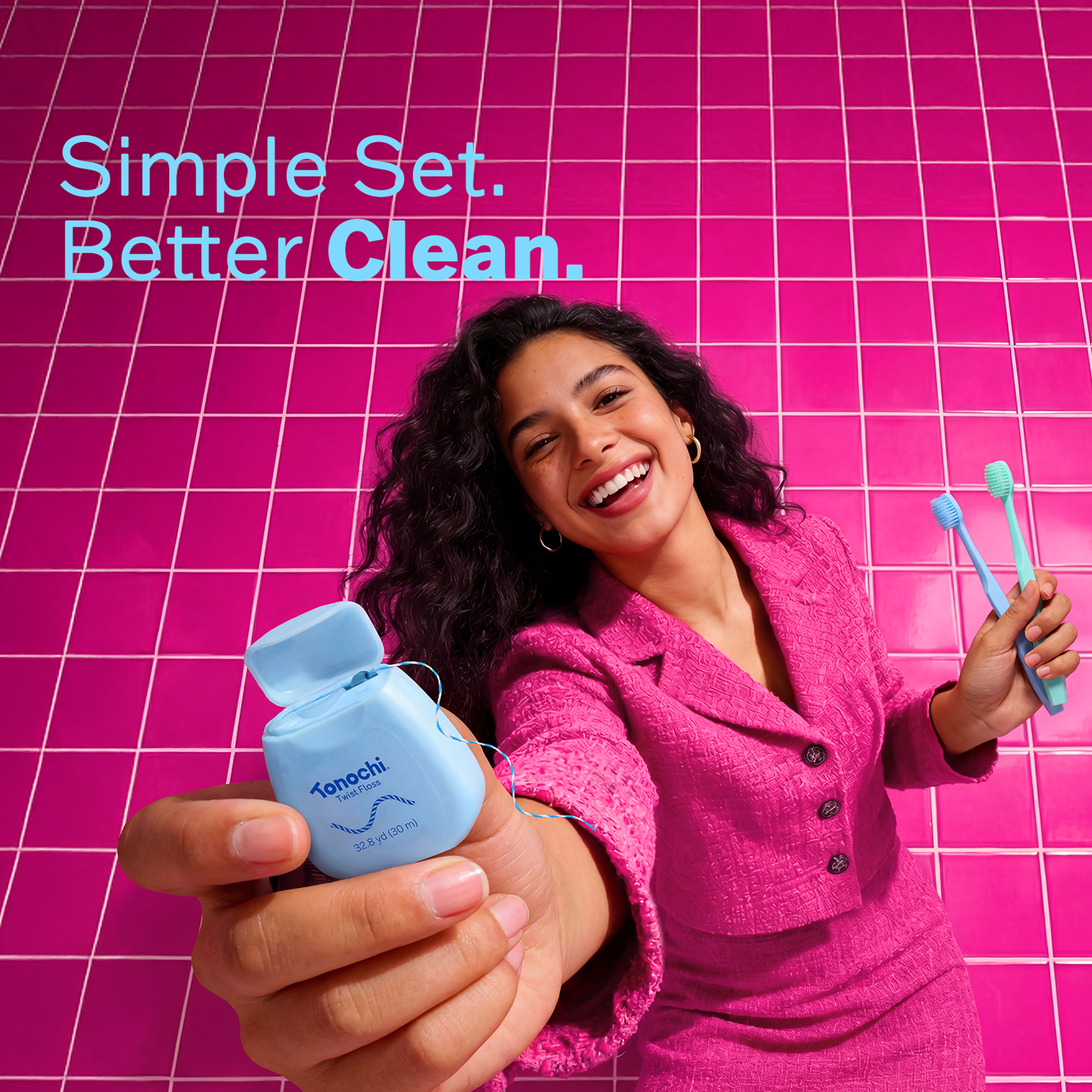 Smiling woman in pink suit holds blue Tonochi dental floss, with the text 