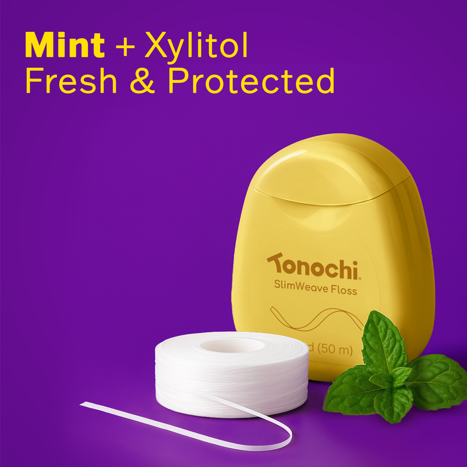 Tonochi SlimWeave dental floss dispenser with fresh mint leaves, highlighting the mint and xylitol infusion.