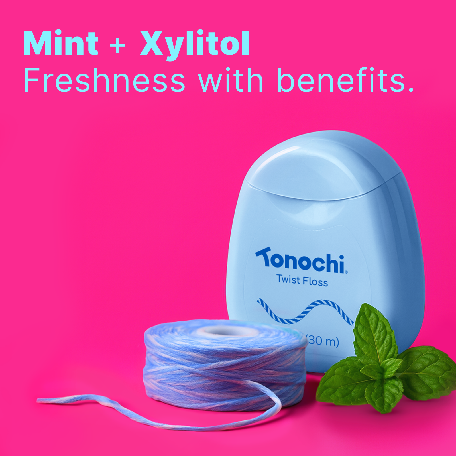 Blue Tonochi Twist Floss dispenser with fresh mint leaves, highlighting the mint and xylitol infusion.