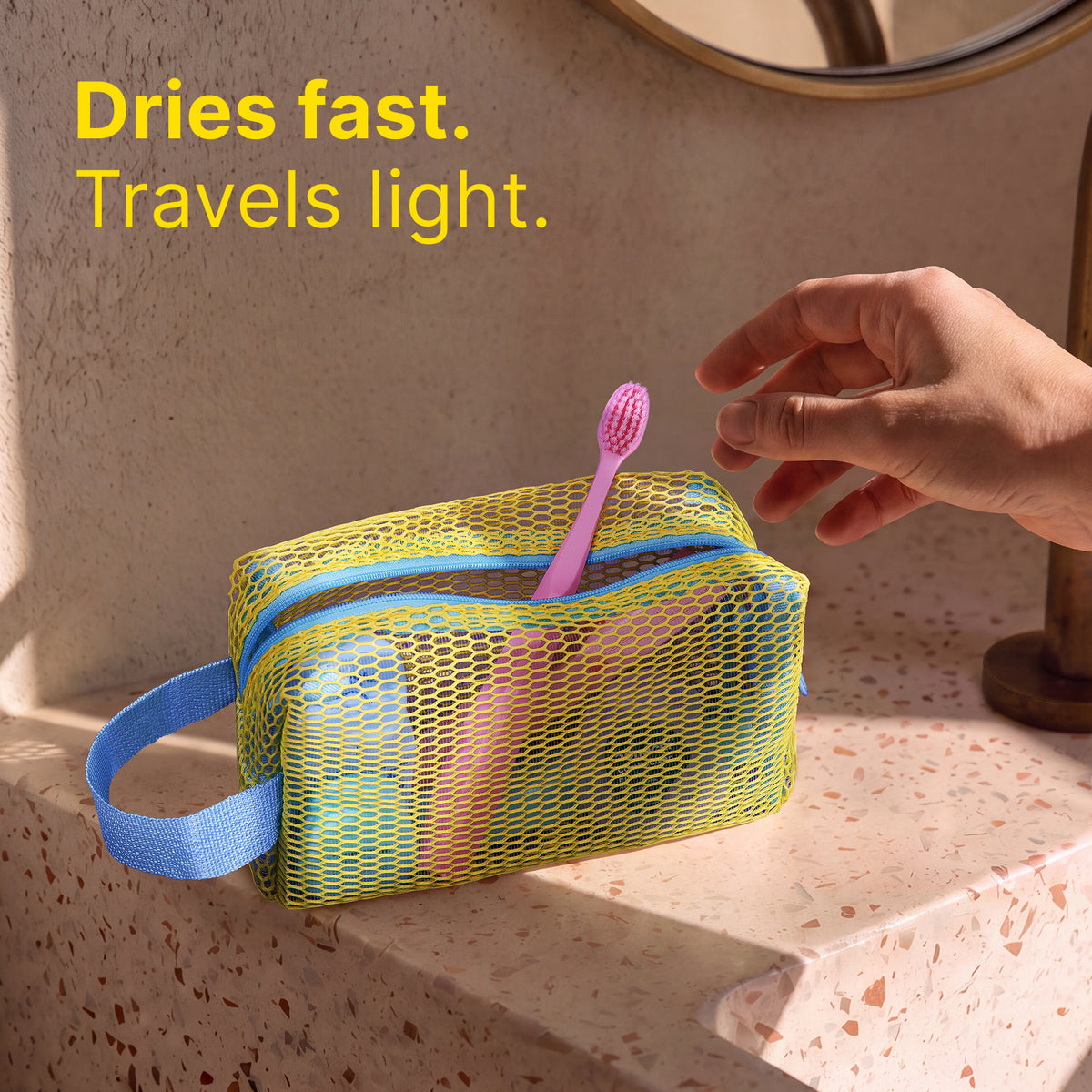 Yellow and blue mesh toiletry pouch holding oral care essentials by a sink
